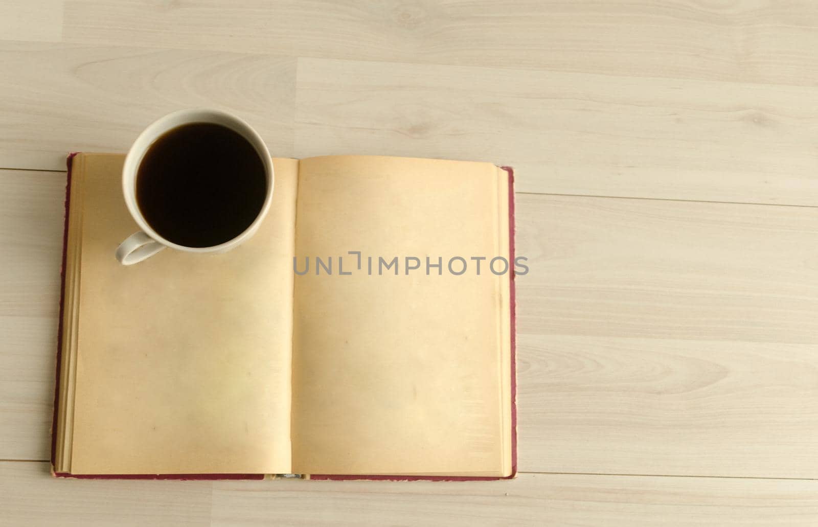 a cup of coffee and an open book on white wooden background.Top view,space for text. by andre_dechapelle