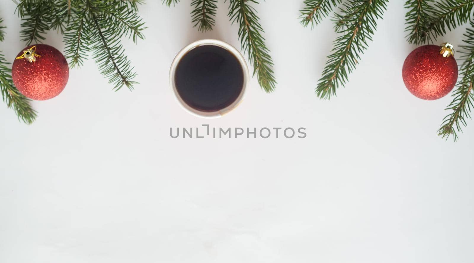 Christmas coffee.Top view, a cup of coffee and two red balls with christmas tree branches on white background,copyspace in the down
