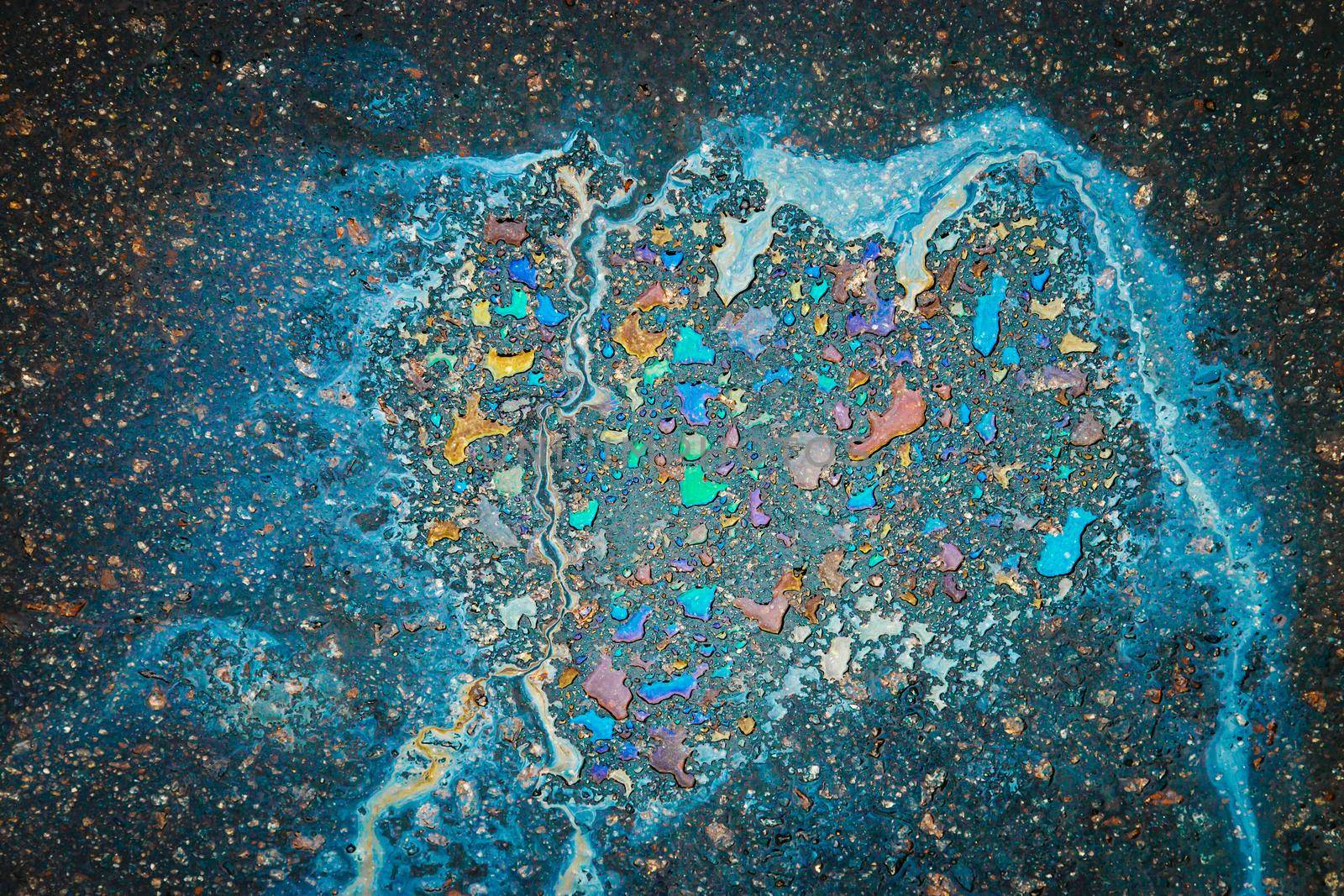 Oil stain on Asphalt road after rain. Abstract close-up background.