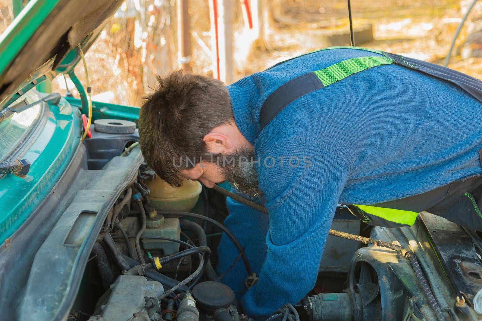 A man repairs an engine in his old car. by Yurich32