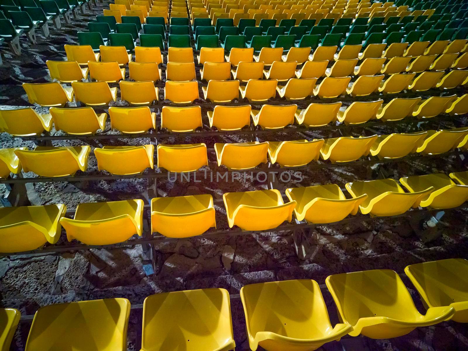 Empty red plastic chairs in the stands of the stadium or amphitheater. Many empty seats for spectators in the stands.  by EdVal