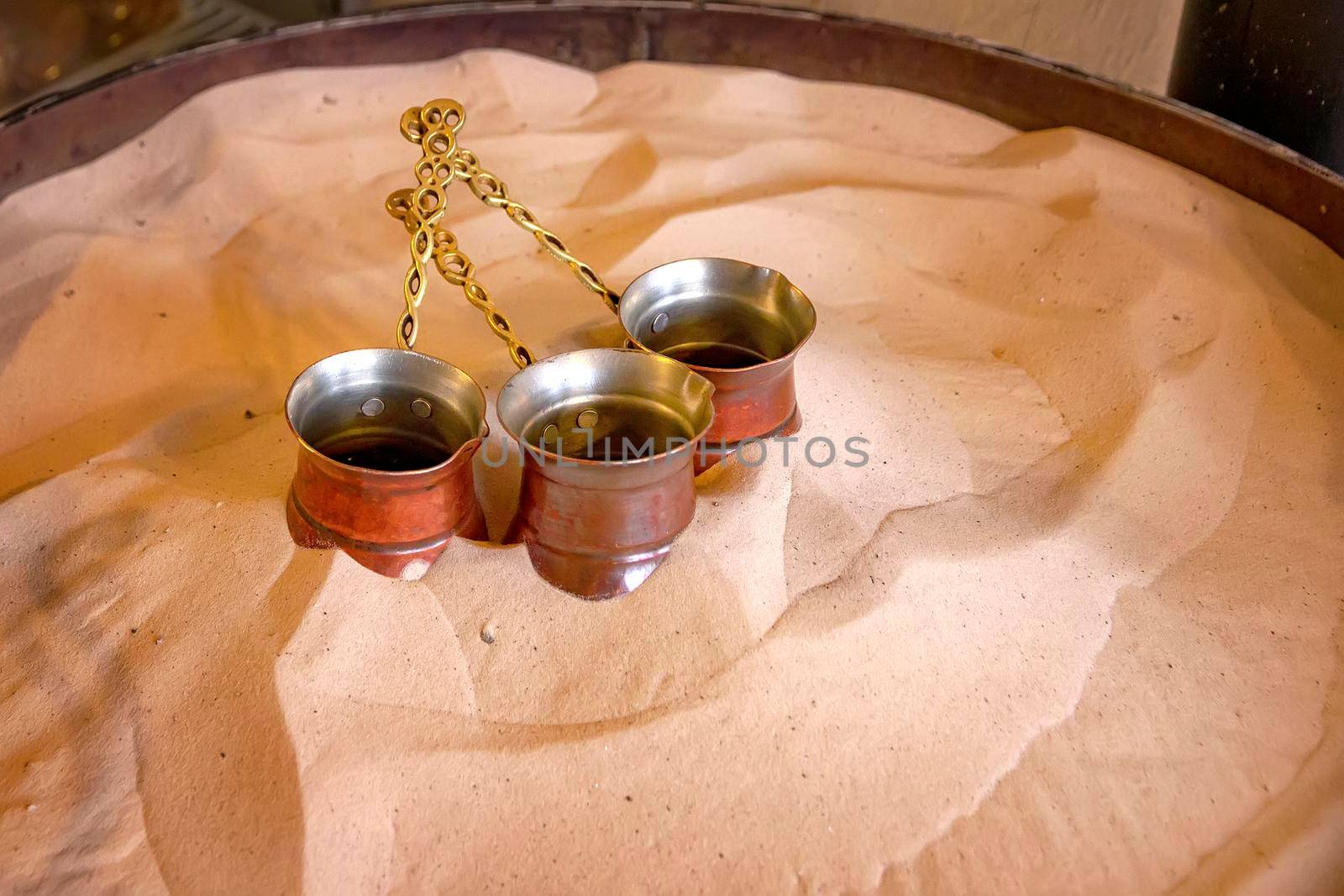 Turkish coffee is made in a traditional way. The copper coffee pots on the hot sand