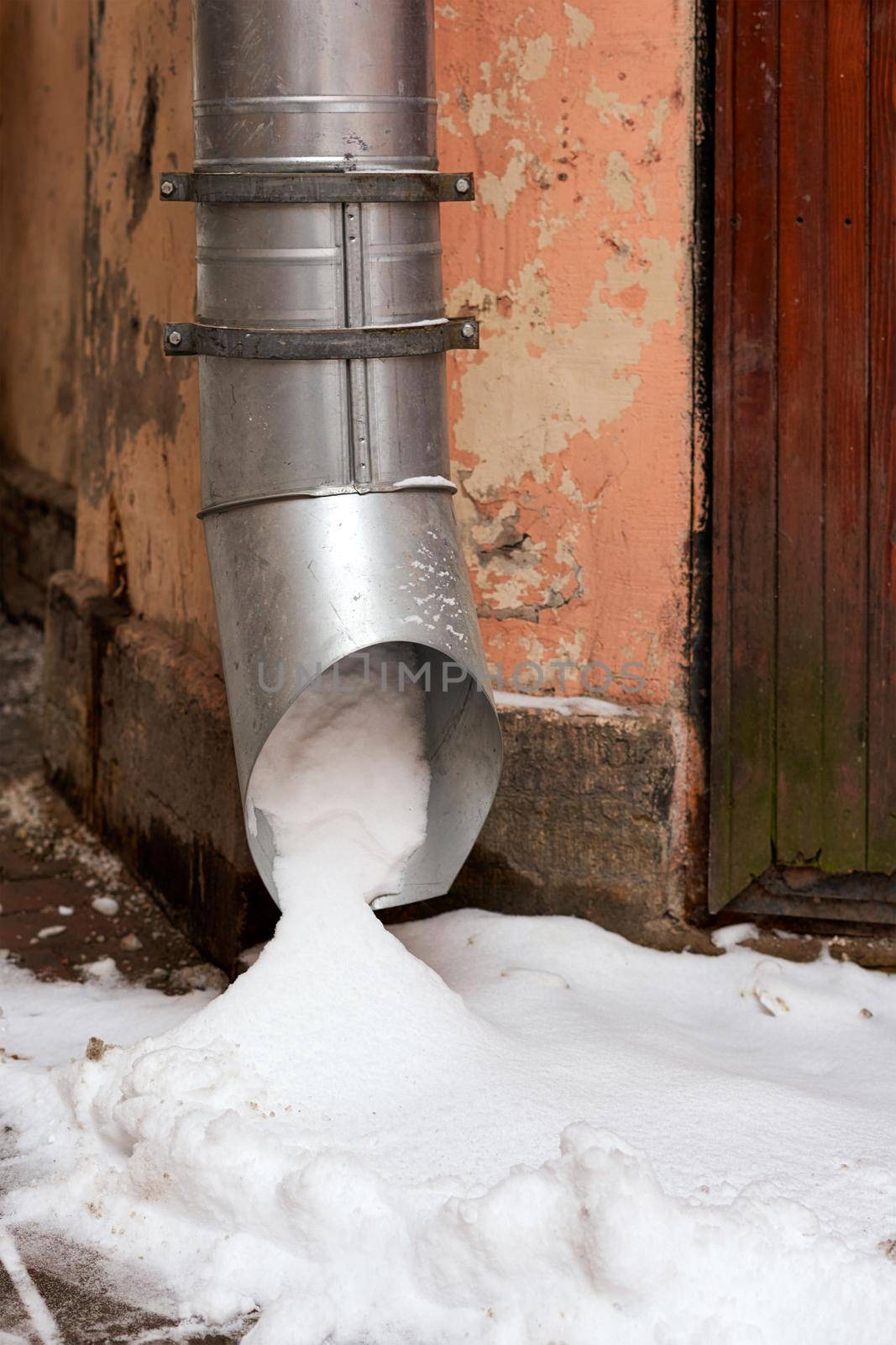 Metal water pipe on the corner of the house is filled with snow by vizland