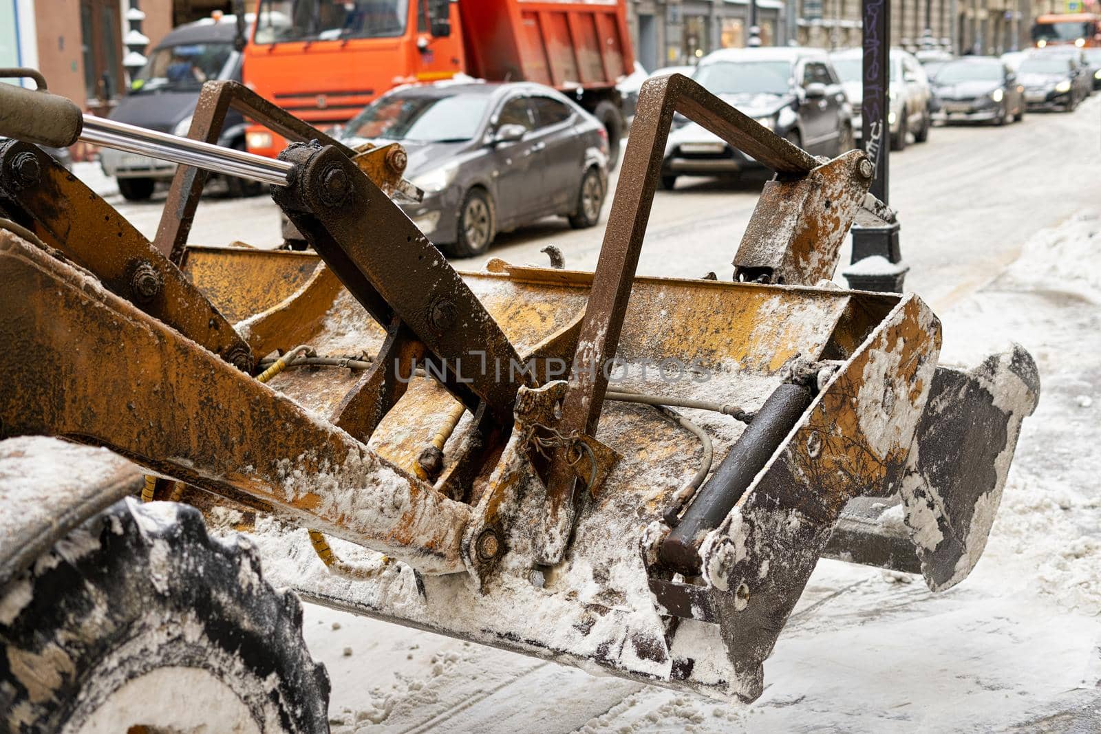 Fragment of a snowplow bucket on the streets of a small European city. Close-up