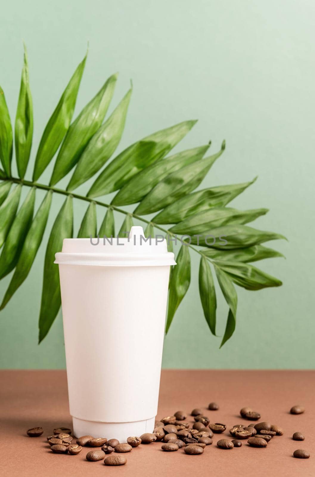 Zero waste and ecology concept. Eco-friendly disposable white paper cup with tropical leaf and coffee beans, mock up design