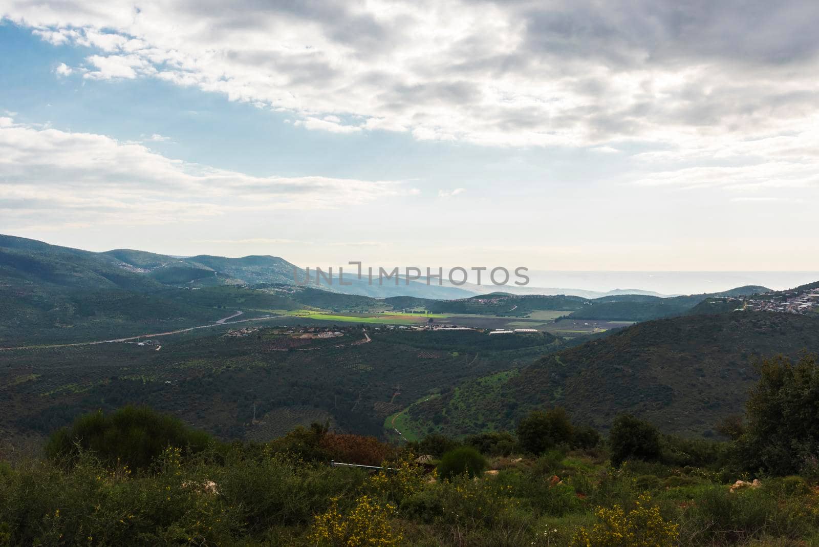 A view of a mountain range and a green valley in the morning at sunrise, against a dramatic back of blue skies and clouds. High quality photo. Travel concept hiking. North District Israel by avirozen