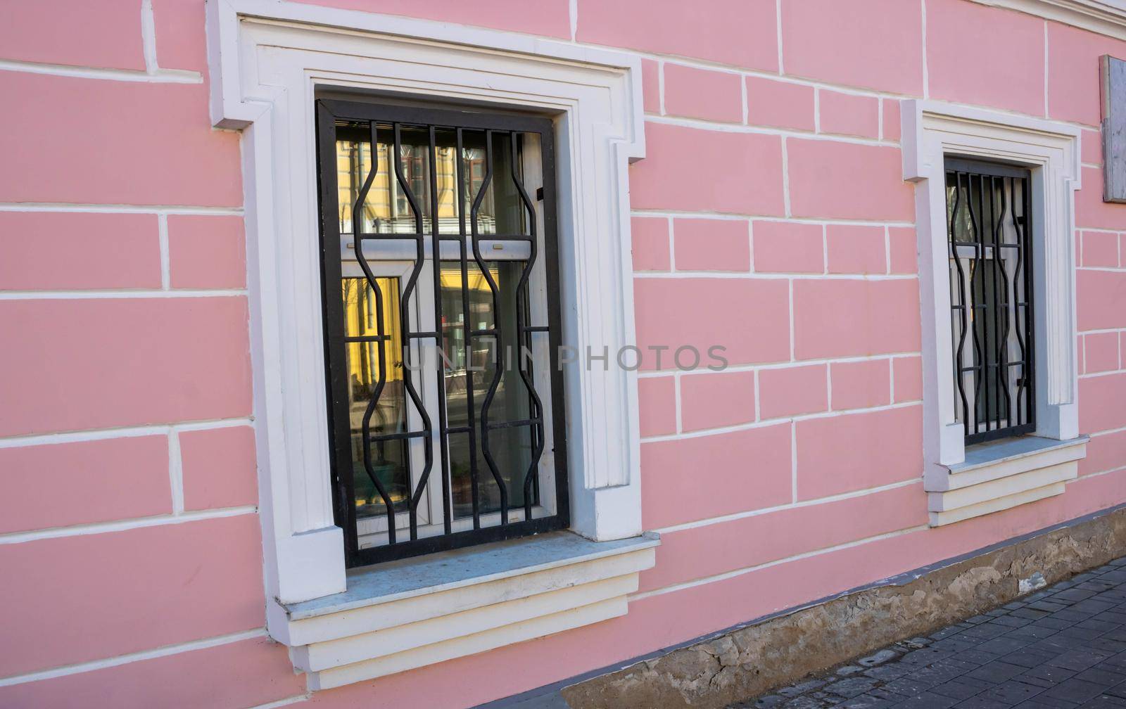 Side view of the pink facade with white windows and bars.