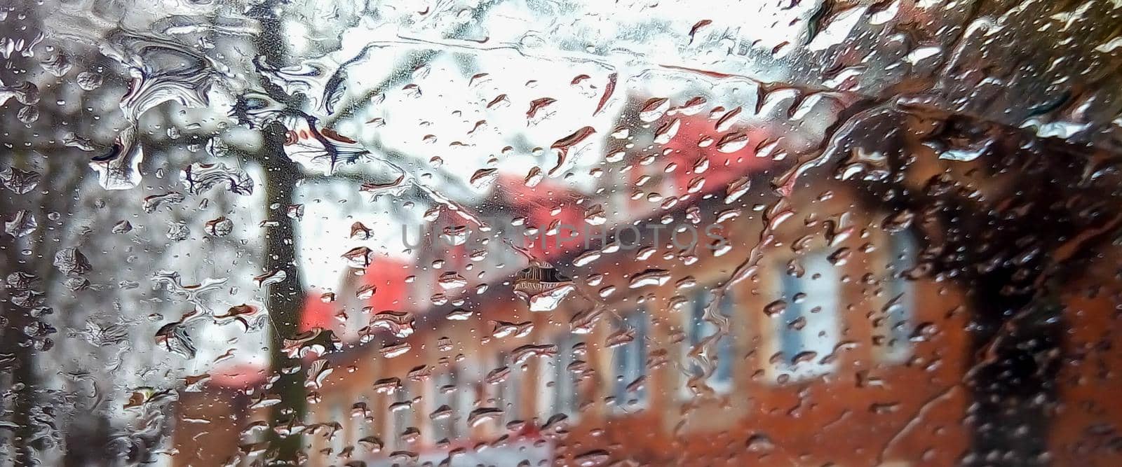 Raindrops on window glass. Rainy city background.