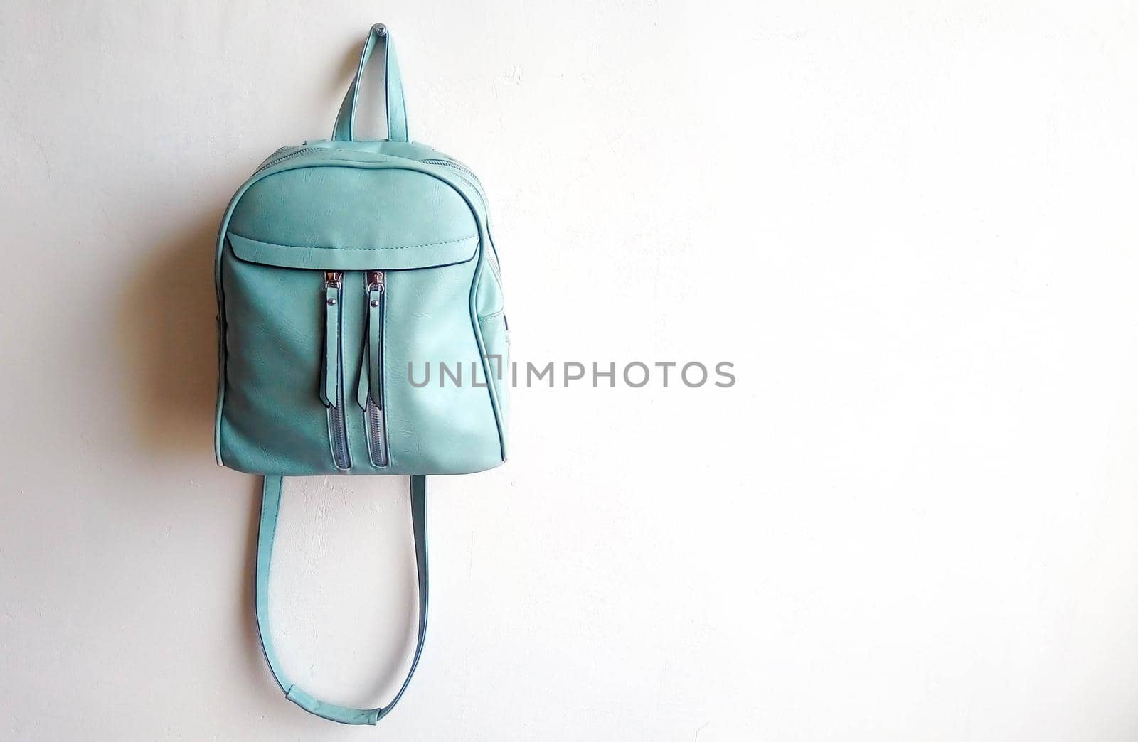 Leather blue women's small backpack with straps on a white background.Space for text.