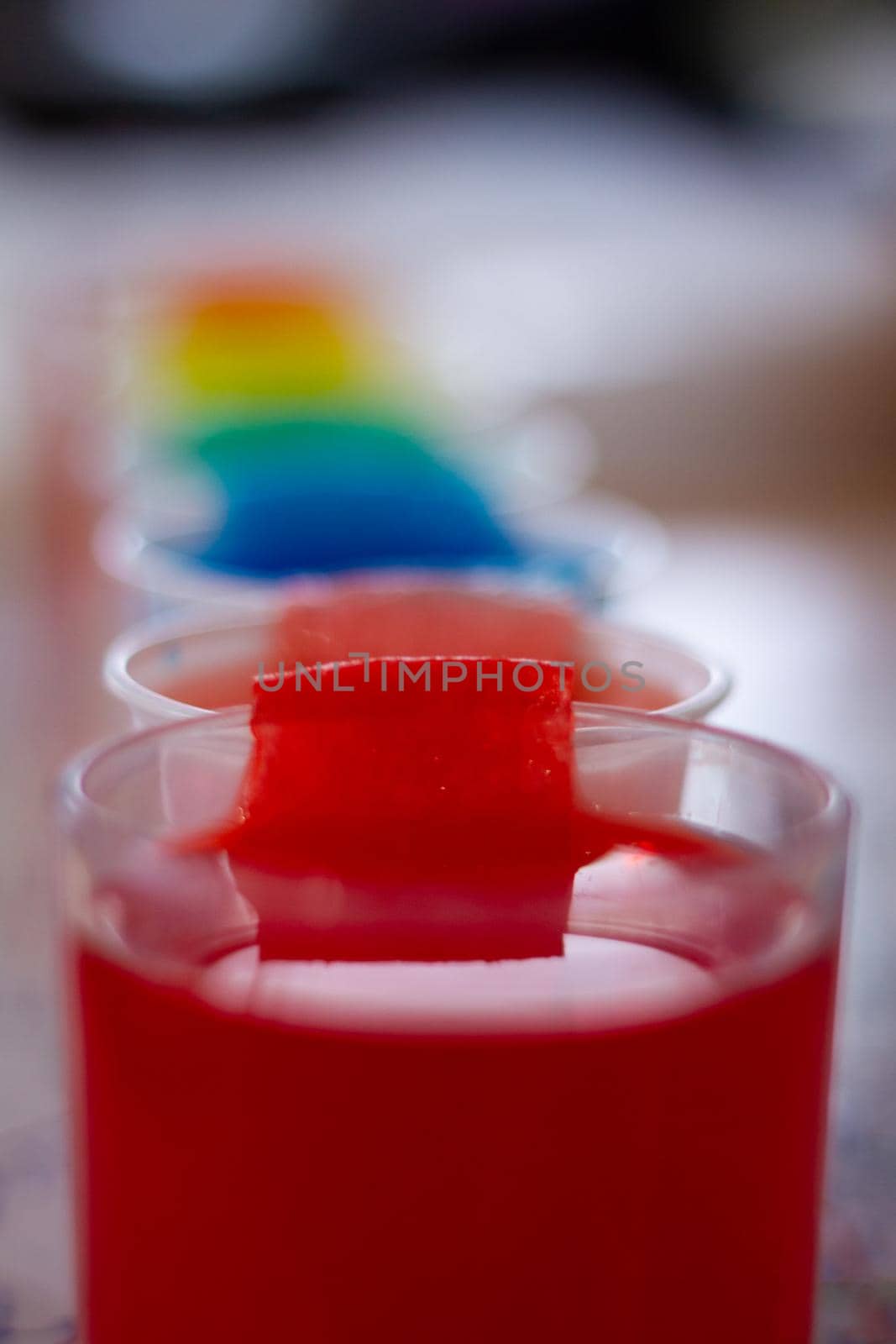 Detail of a group of glasses full of rainbow coloured liquids