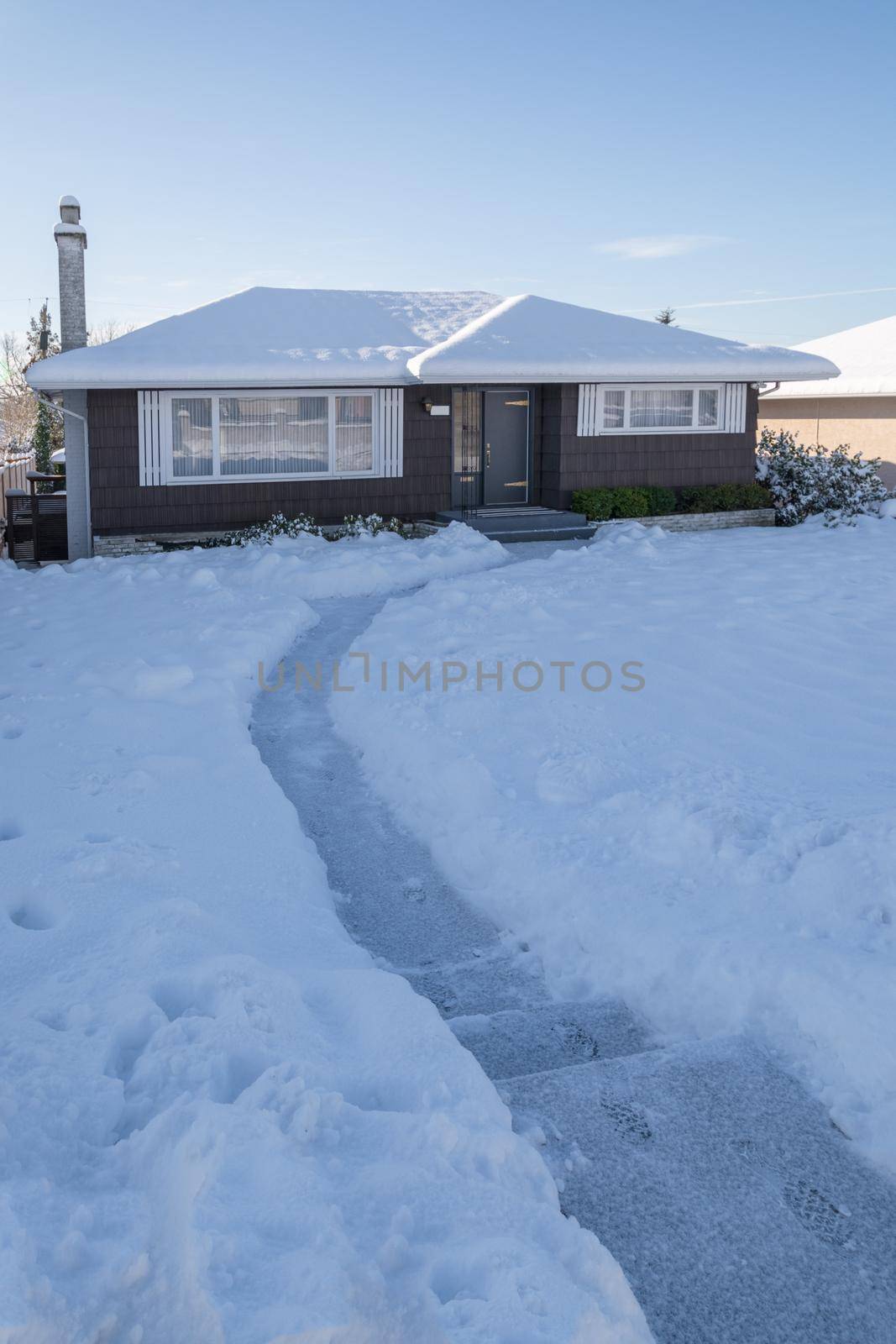 Pathway over front yard leading to average house cleaned from the snow