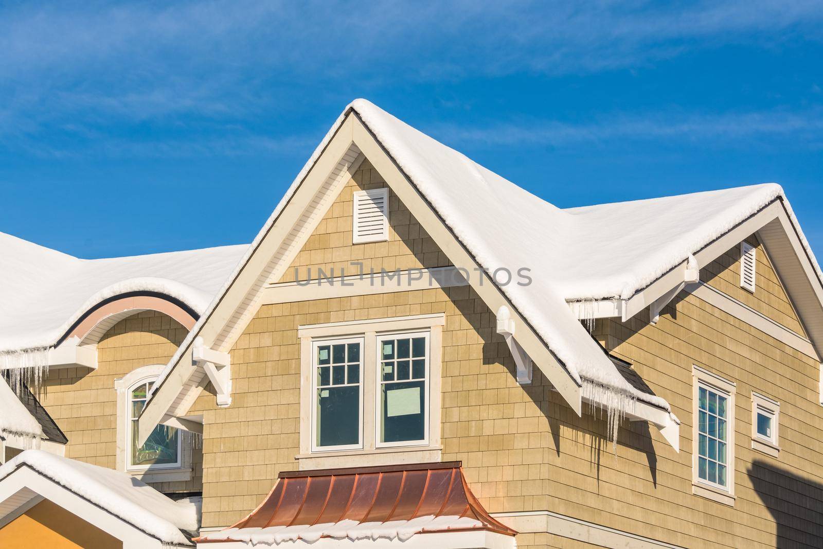 Top of new luxury residential house in snow. North American family house on winter sunny day