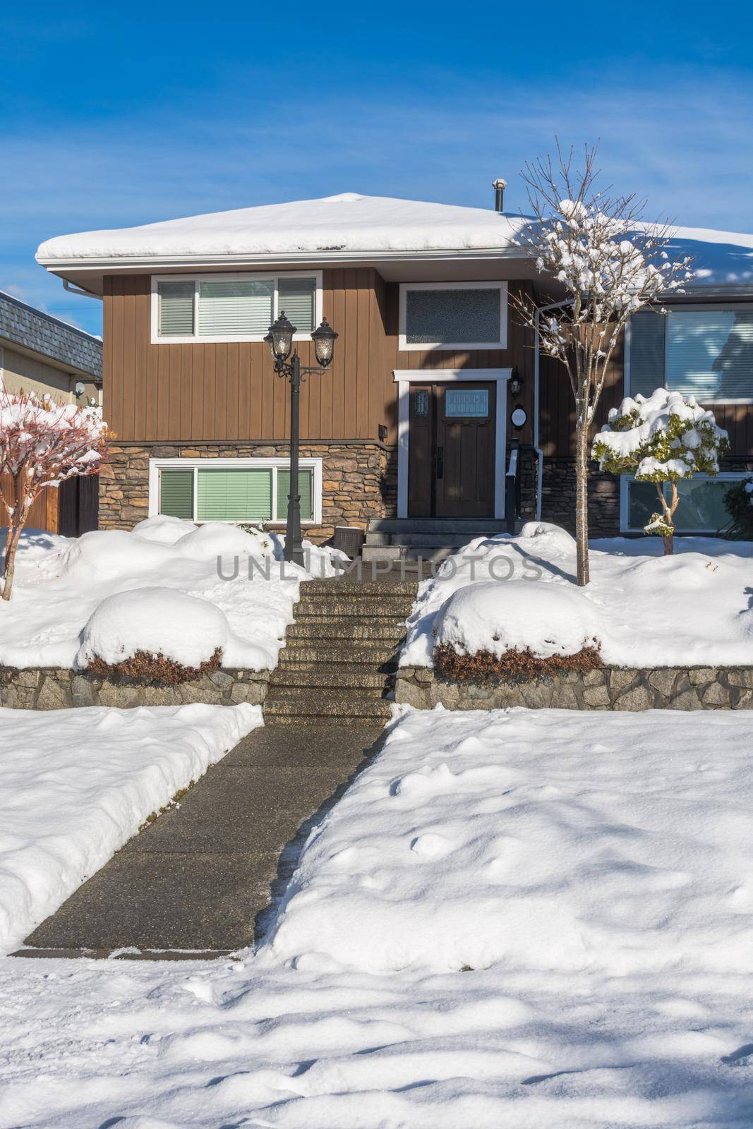 Pathway over front yard leading to average house cleaned from the snow