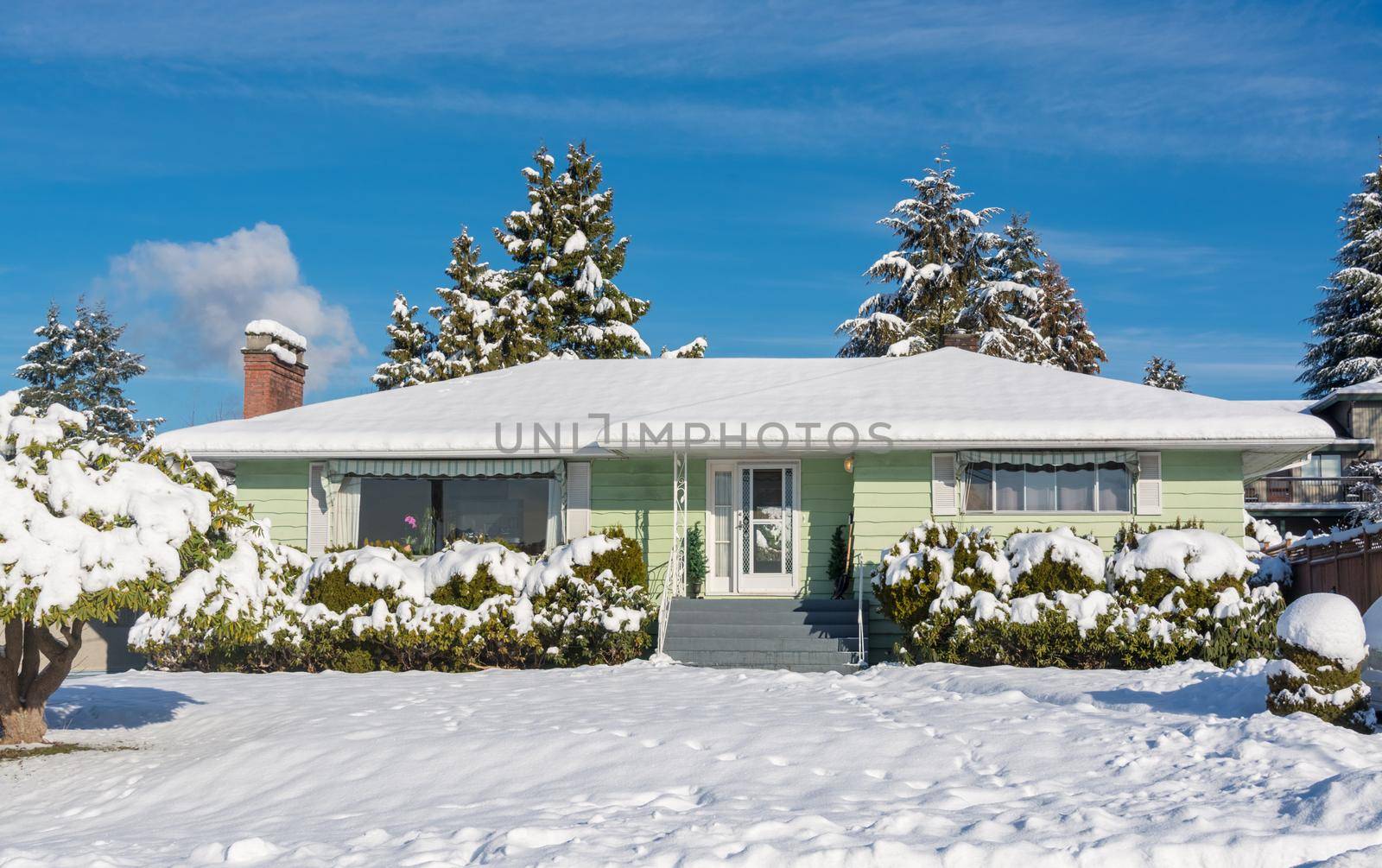 Family residential house with front yard in snow. North American house on winter sunny day