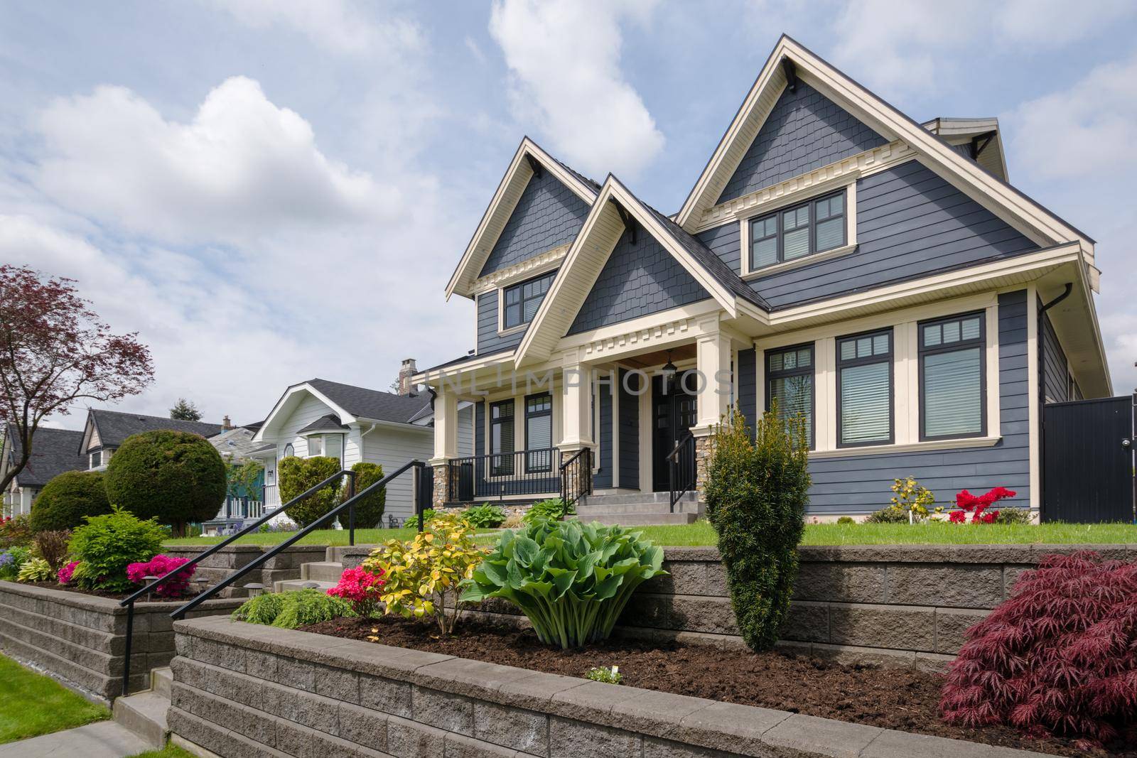 Luxury residential house with front yard over land terraces. Big family house with nice landscaping in front