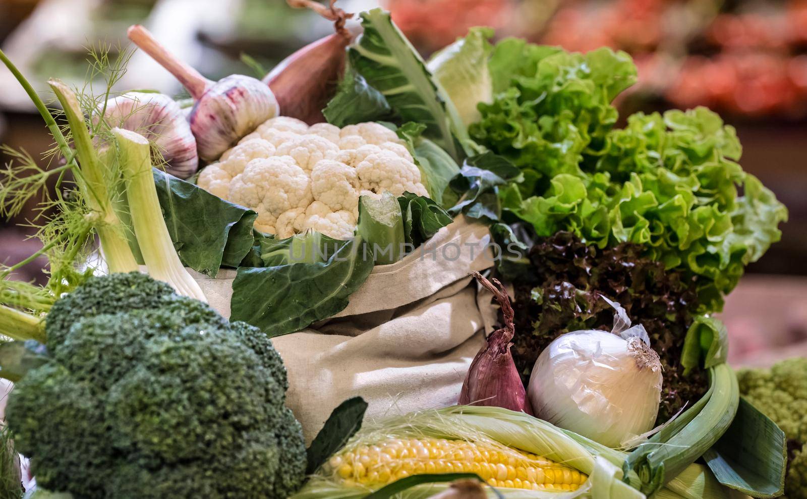 Display of fresh ripe organic broccoli, salad with greens and vegetables in cotton bag at the weekend farmer's market by vectorart