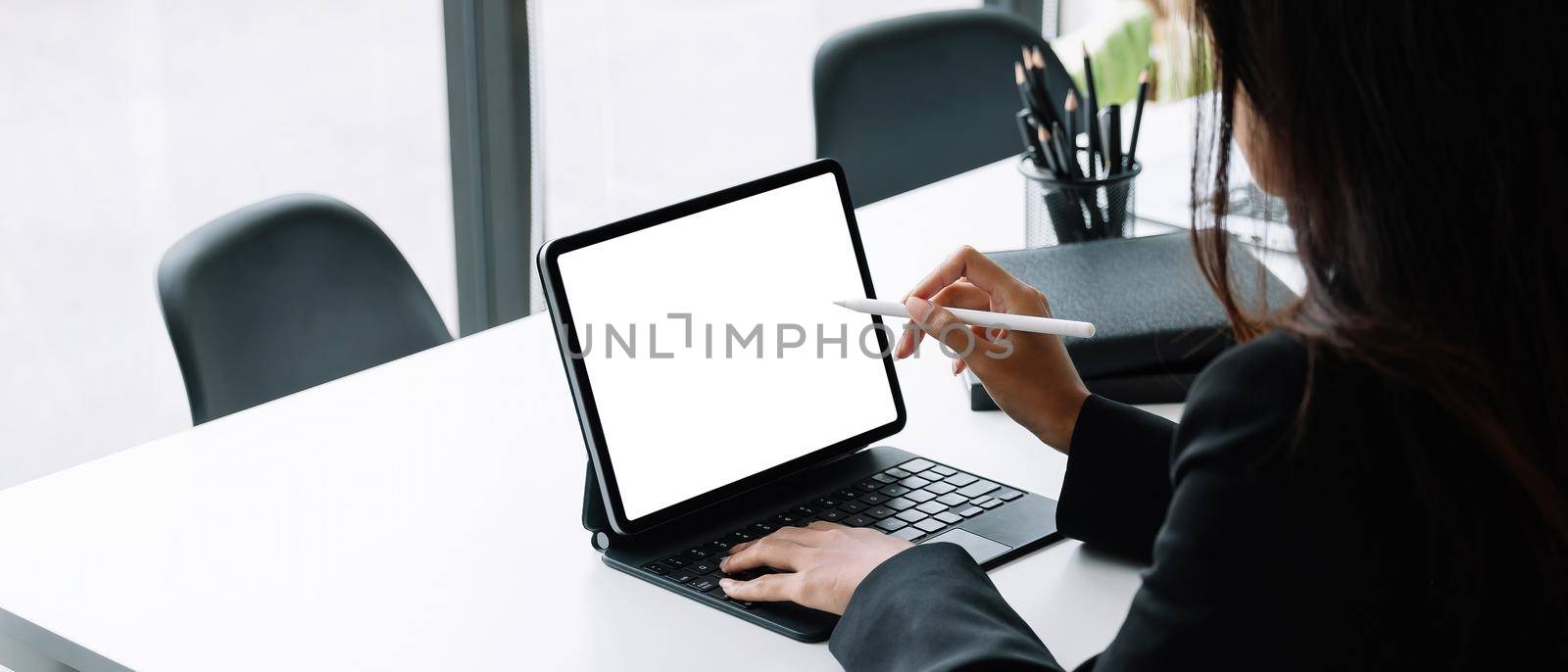 Businesswoman working with a stylus pen on a digital tablet with a laptop computer in a modern office. by nateemee