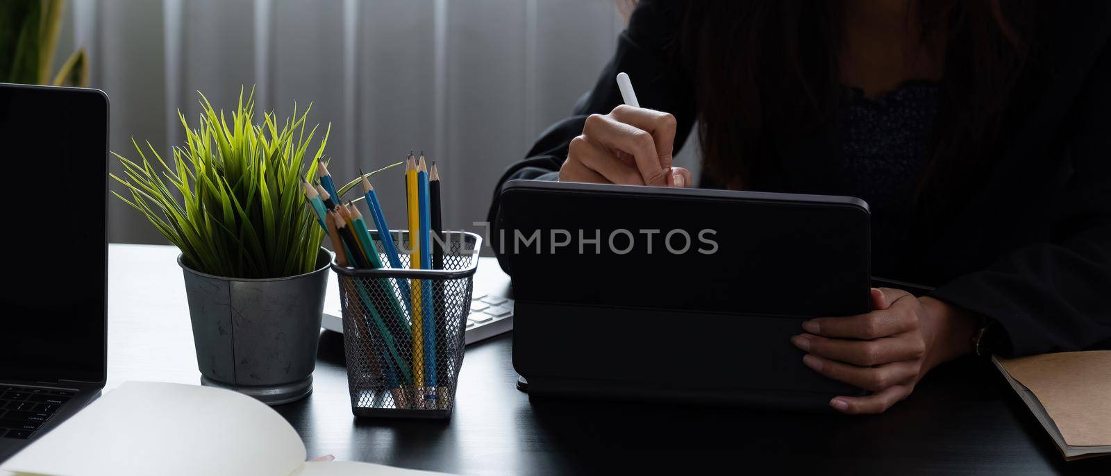 Close up business woman holds pen stylus with digital tablet at office by nateemee
