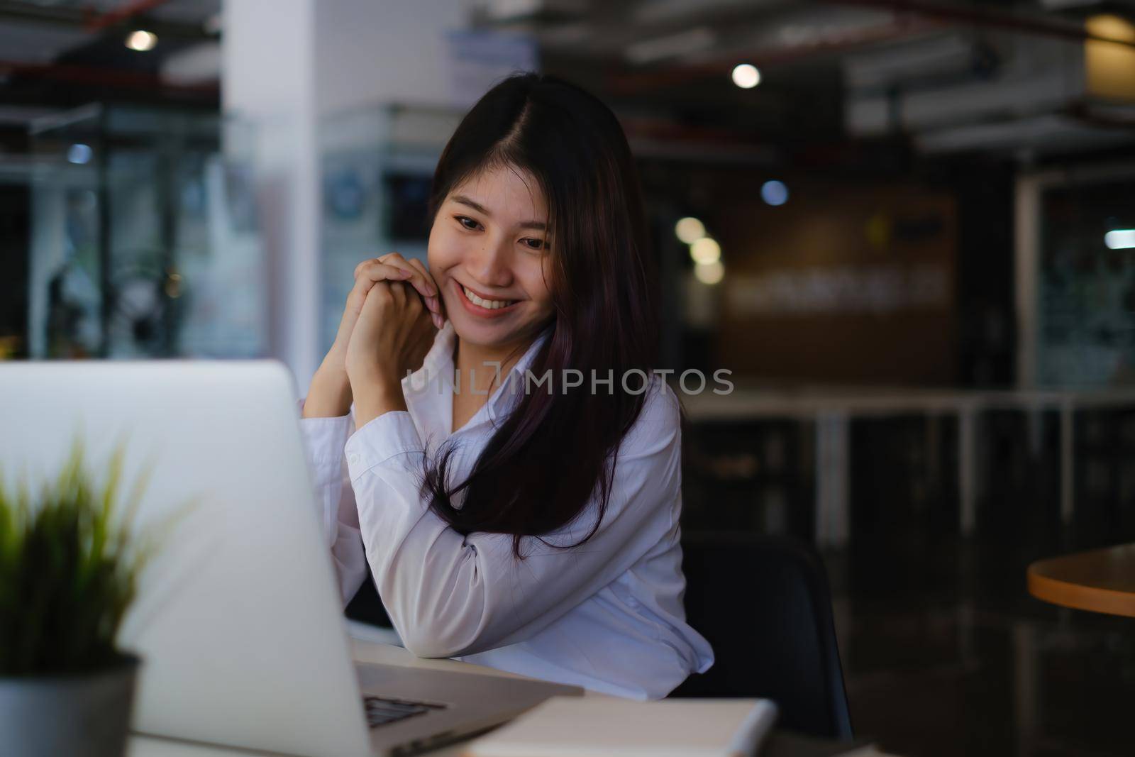Joyful businesswoman sitting at desk looking at laptop screen talking with friend make informal video call