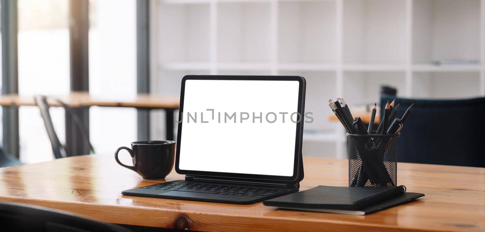 Cropped shot of workplace with tablet blank screen and office supplies in simple workspace by nateemee