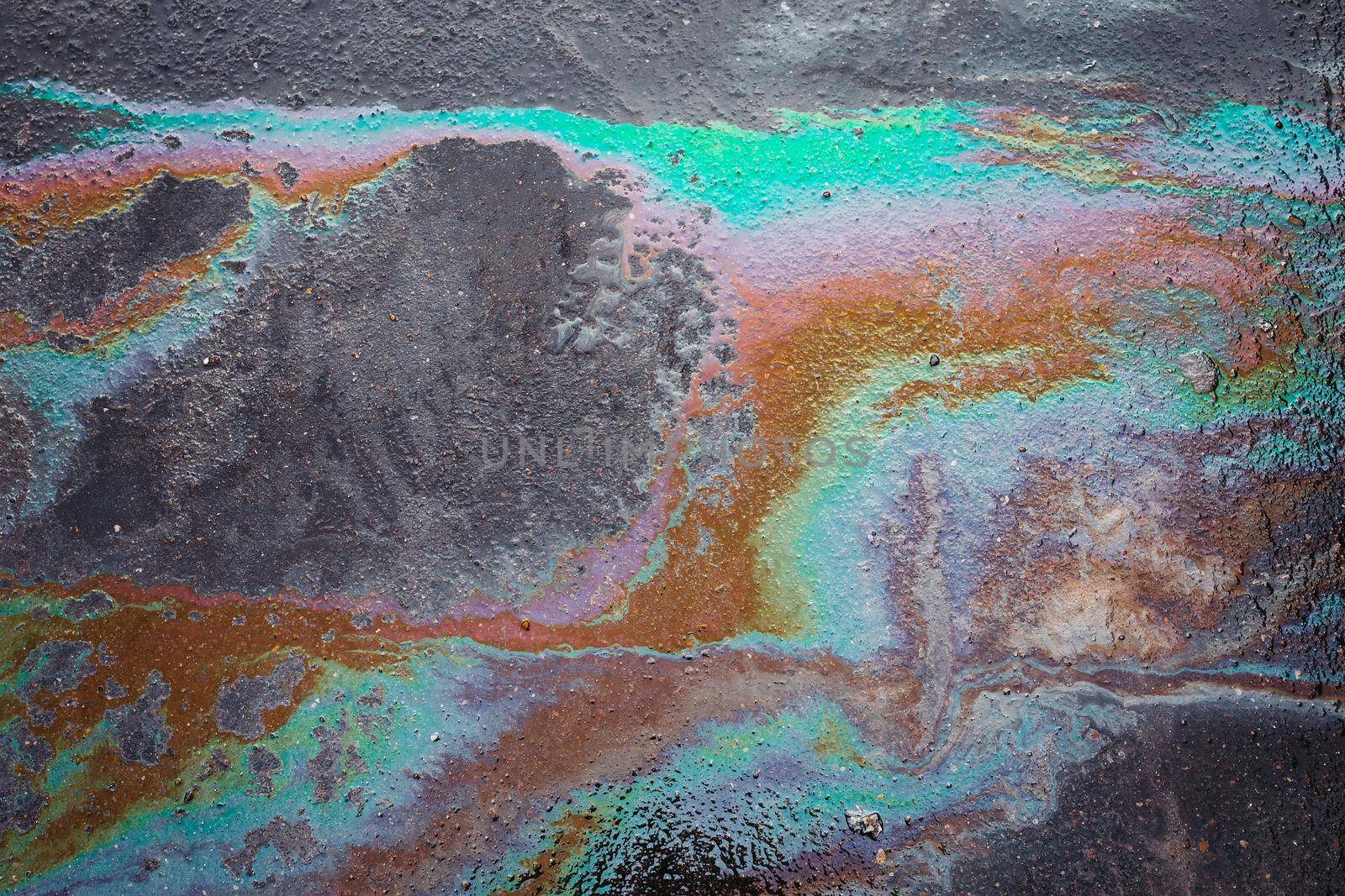 Color gasoline fuel spot on black asphalt, industrial concept. Beautiful abstract colorful background