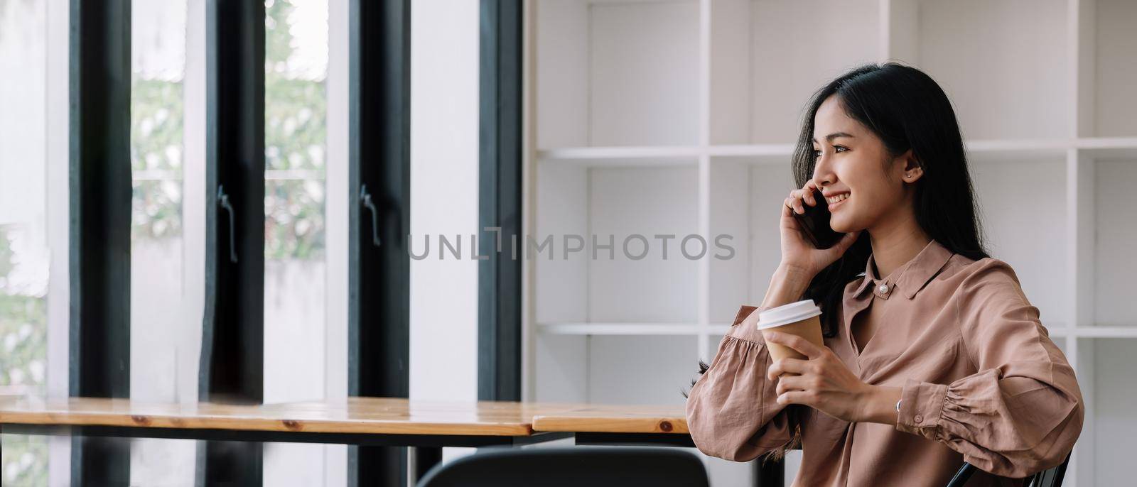 Young business woman sitting having a phone call at home office, working.