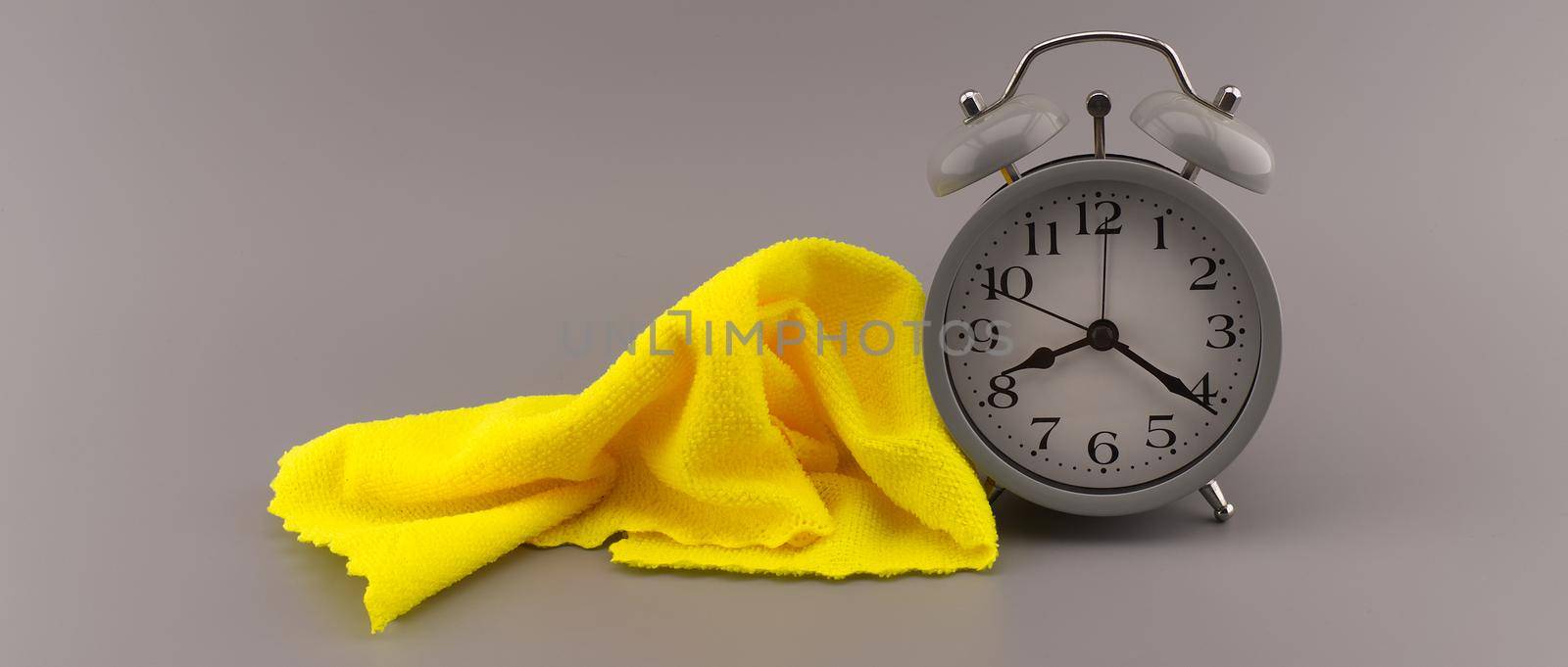 Color trends themed still life with grey alarm clock placed near yellow textile