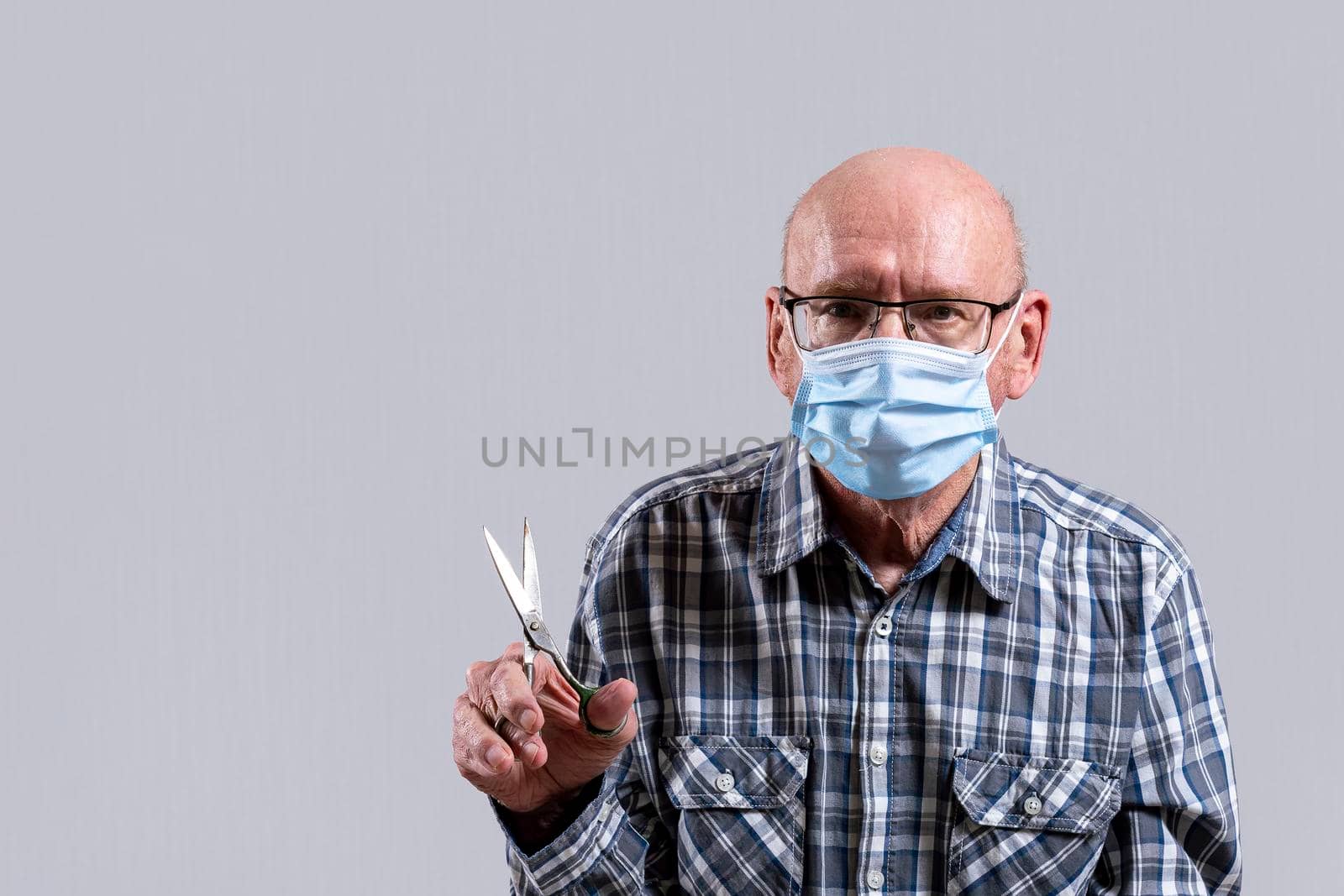 Old bald man with glasses and medical mask with steel scissors in his hand. Copy space. by Essffes