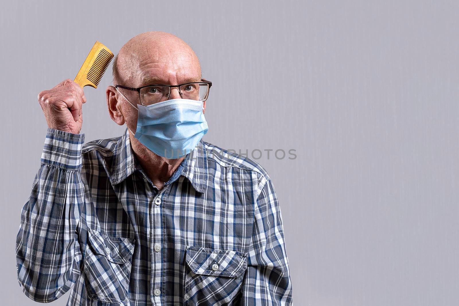 Old bald man with glasses and medical mask with hairbrush in his hand. Copy space. by Essffes