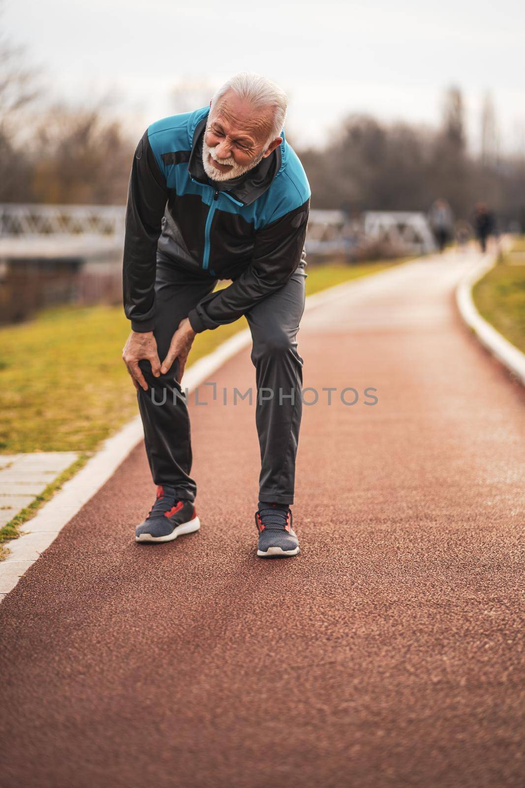 Active senior man is having pain in knee while jogging.