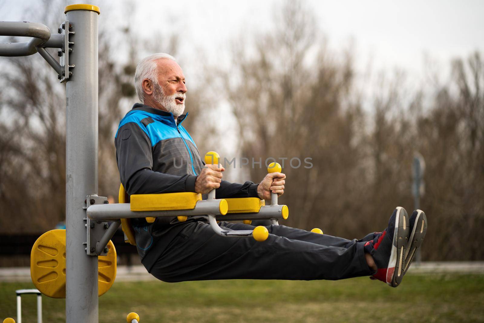 Active senior man is exercising on outdoor gym. Healthy retirement lifestyle.