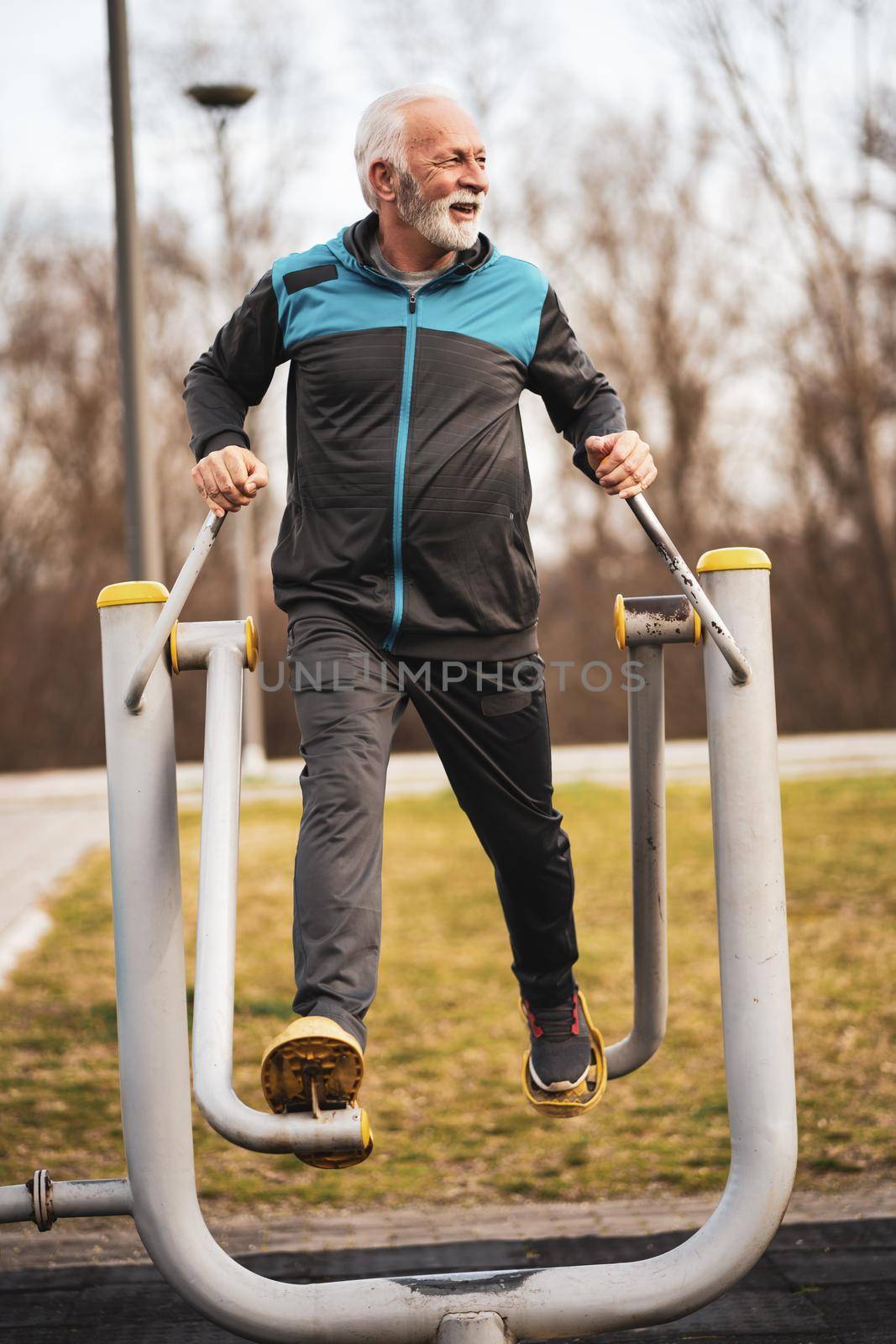 Active senior man is exercising on outdoor gym. Healthy retirement lifestyle.