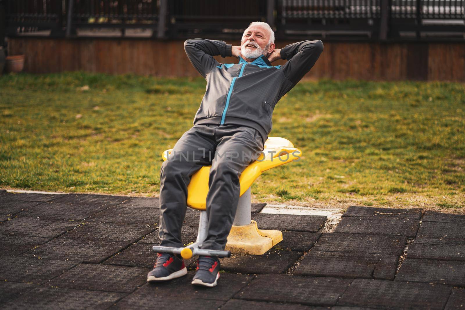 Active senior man is exercising on outdoor gym. Healthy retirement lifestyle.