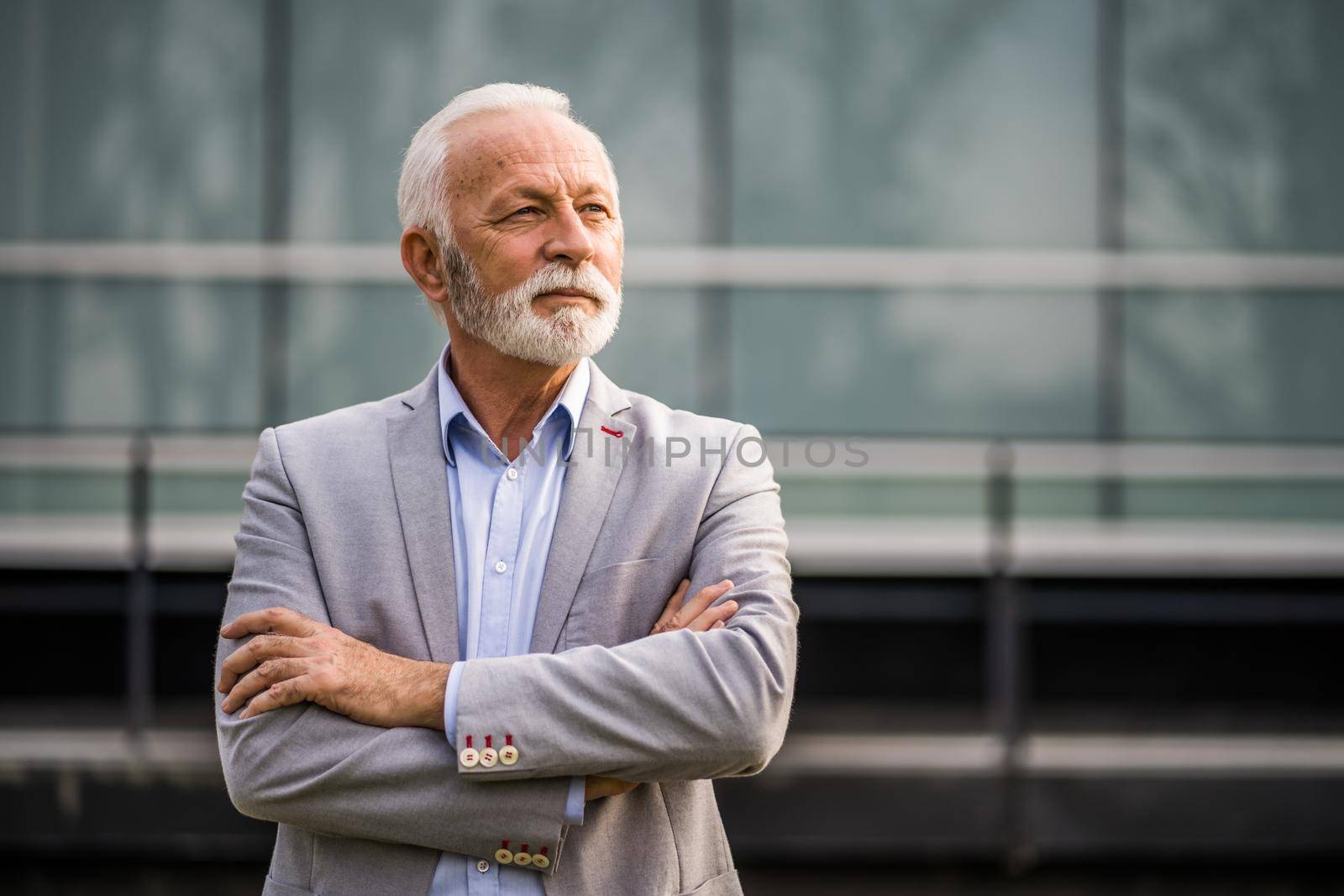 Outdoor portrait of senior businessman in front of company building.