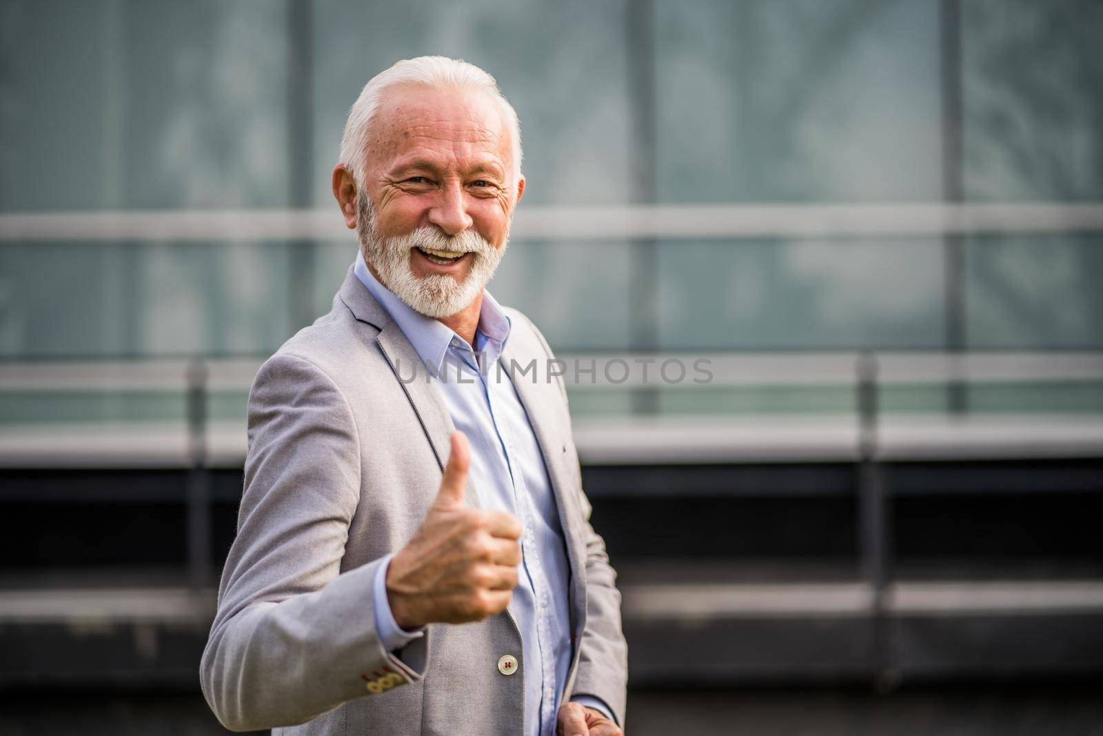 Outdoor portrait of senior businessman in front of company building.