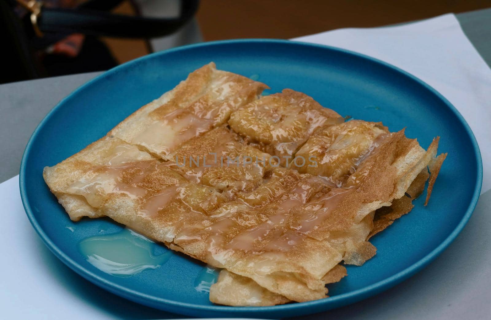 sweet crispy banana roti on blue dish by baworn47