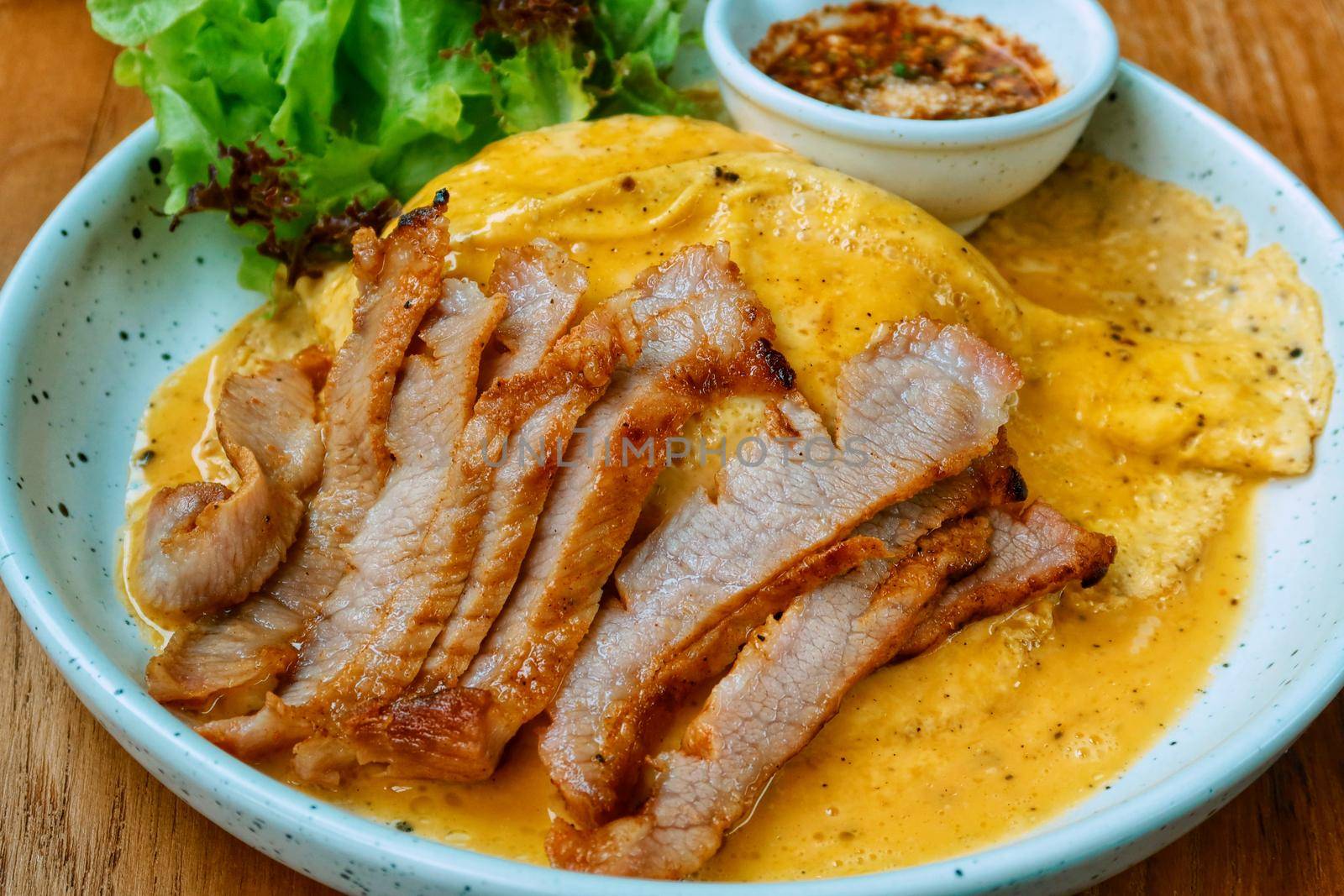 top view of grilled pork neck with omelette and spicy sauce