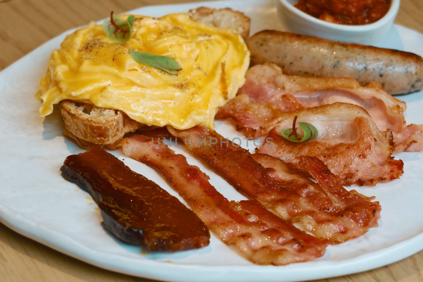 american breakfast set on white dish, bacon ,sausage ,scramble egg, tomato sauce