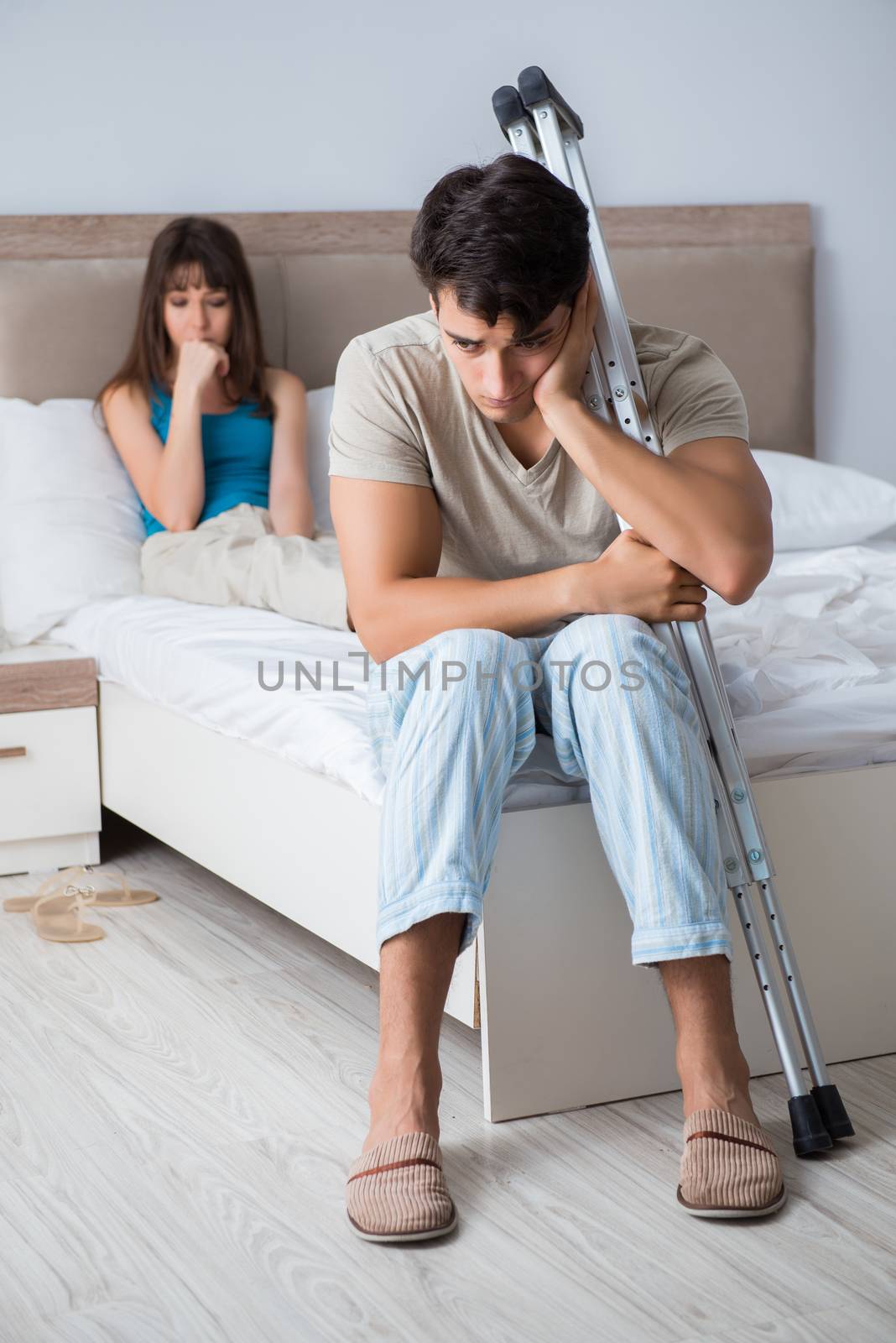 Young wife supporting husband on crutch after injury