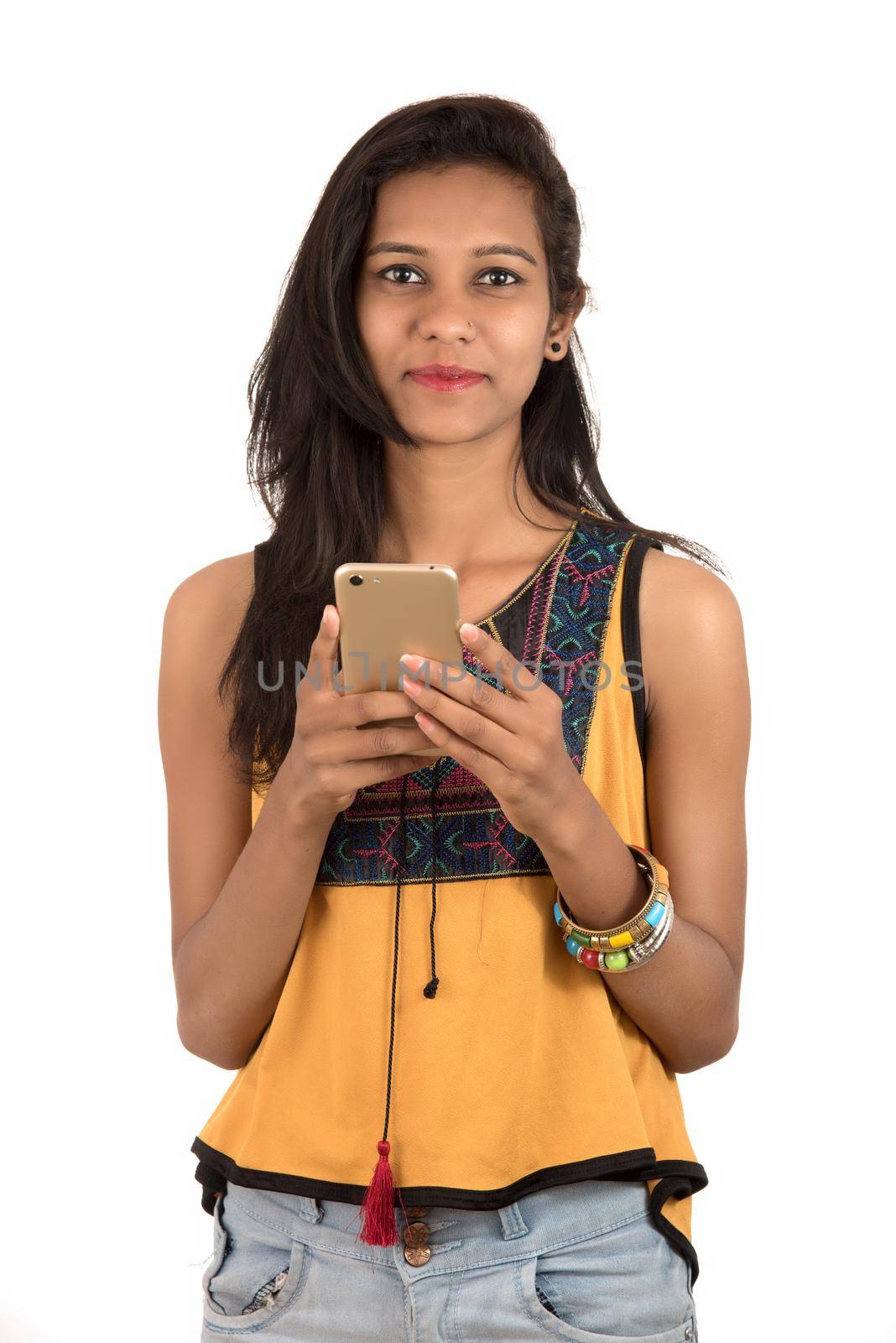 Portrait of a happy young girl using mobile phone isolated over white background