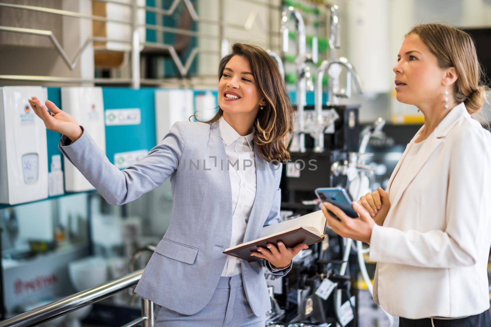 Businesswoman owning small business bath store. She is talking with a customer who is choosing the goods.