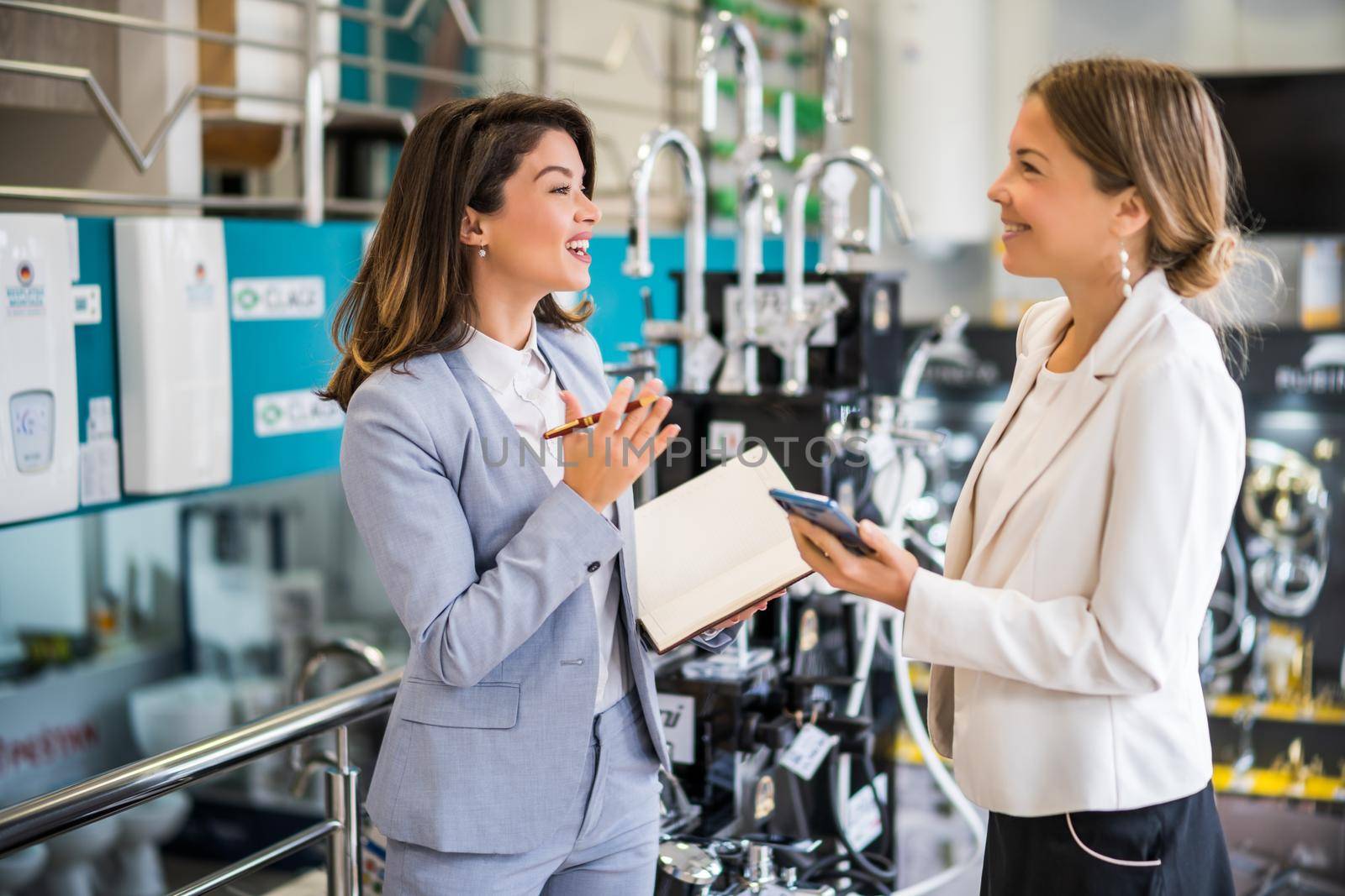 Businesswoman owning small business bath store. She is talking with a customer who is choosing the goods.