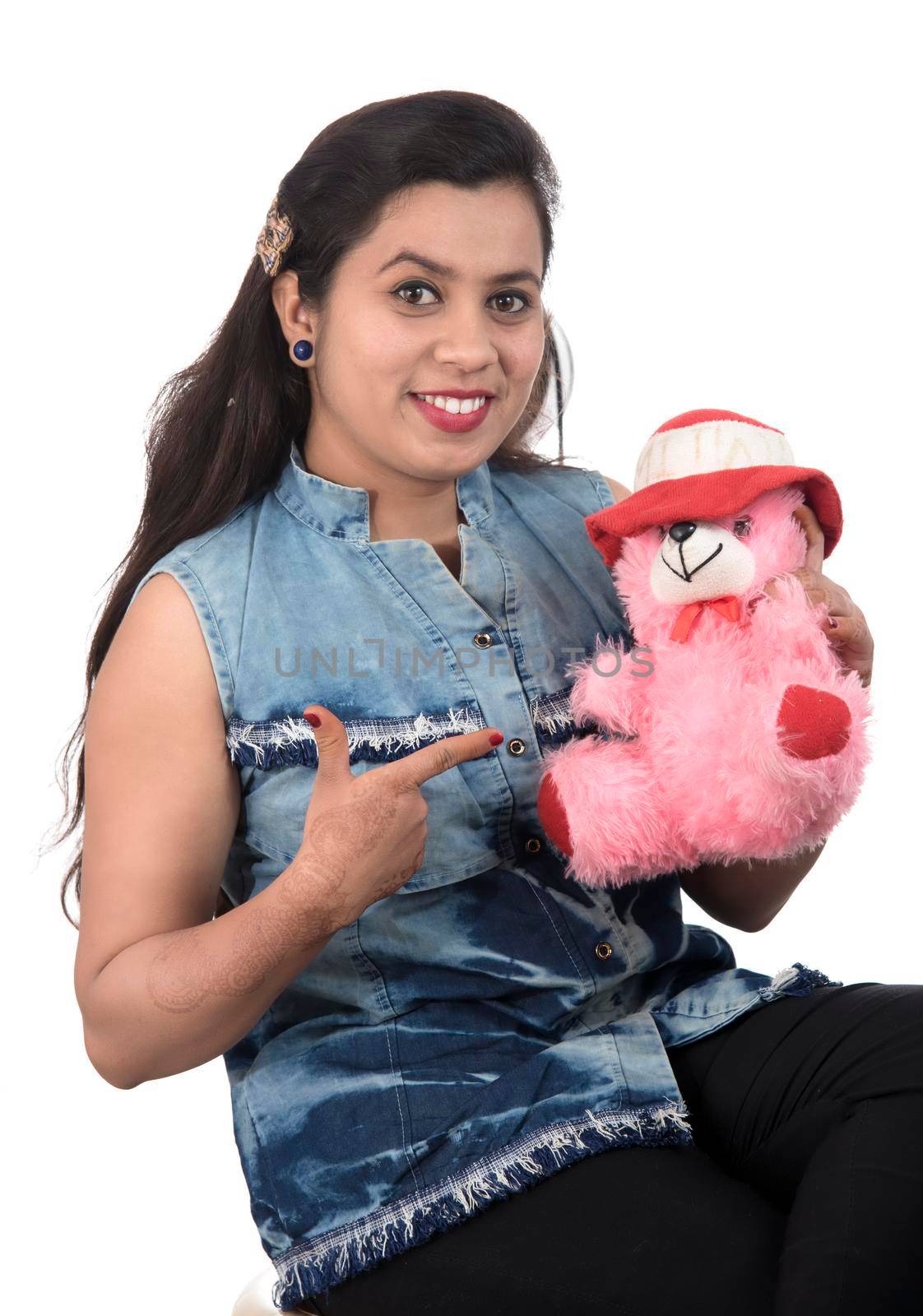 Beautiful young girl holding and playing with a teddy bear toy on a white background.