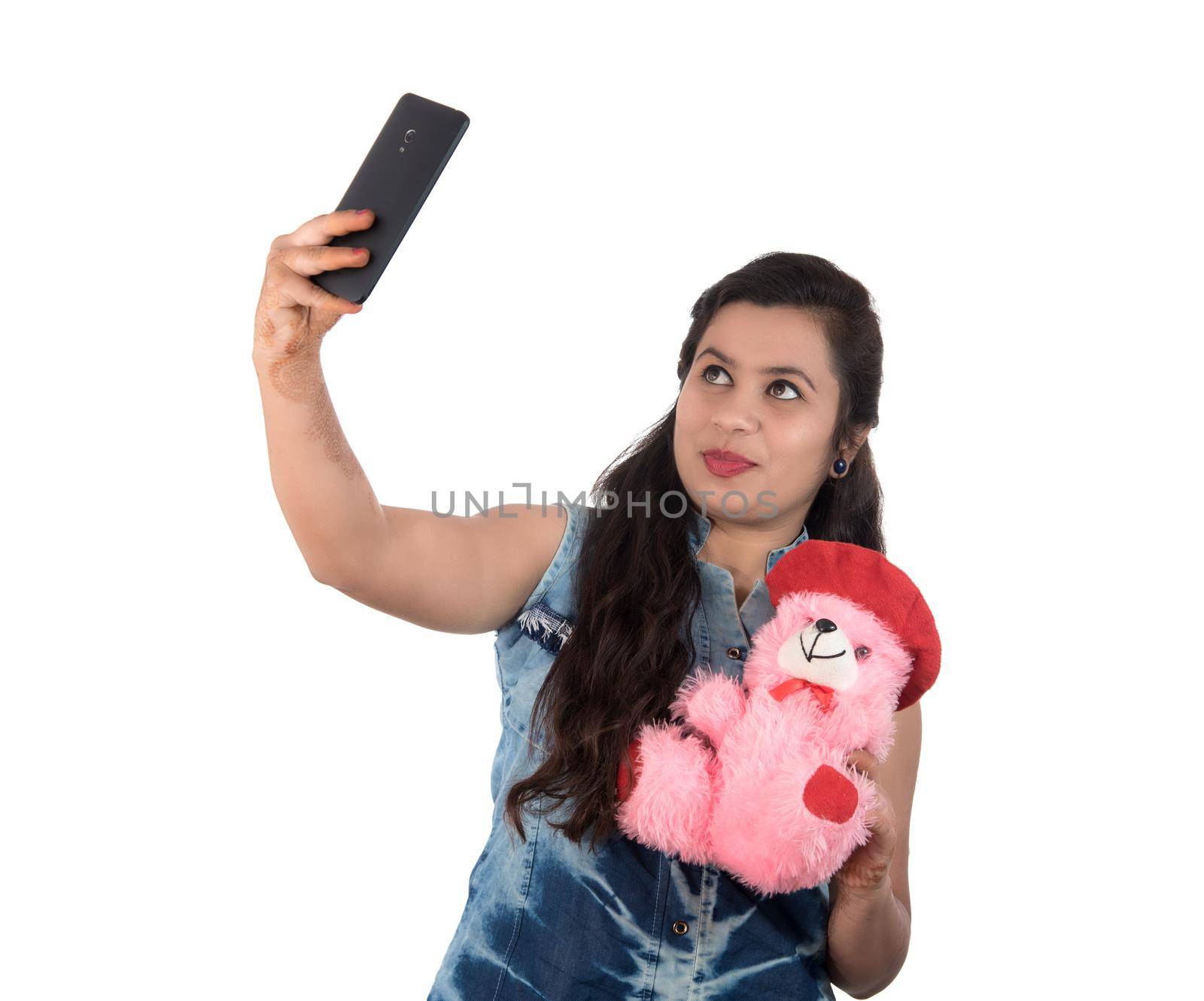 Woman taking picture or selfie with mobile phone and holding teddy bear