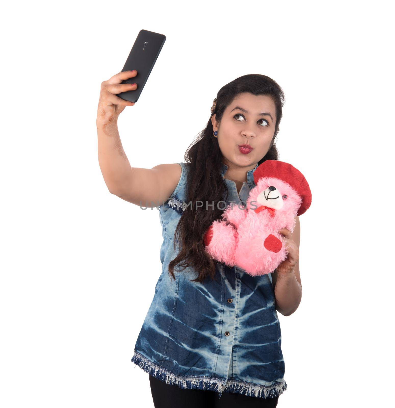 Woman taking picture or selfie with mobile phone and holding teddy bear