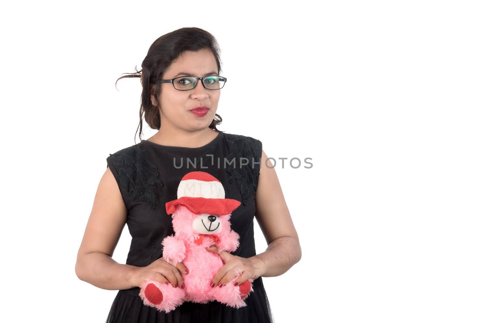 Beautiful young girl holding and playing with a teddy bear toy on a white background.