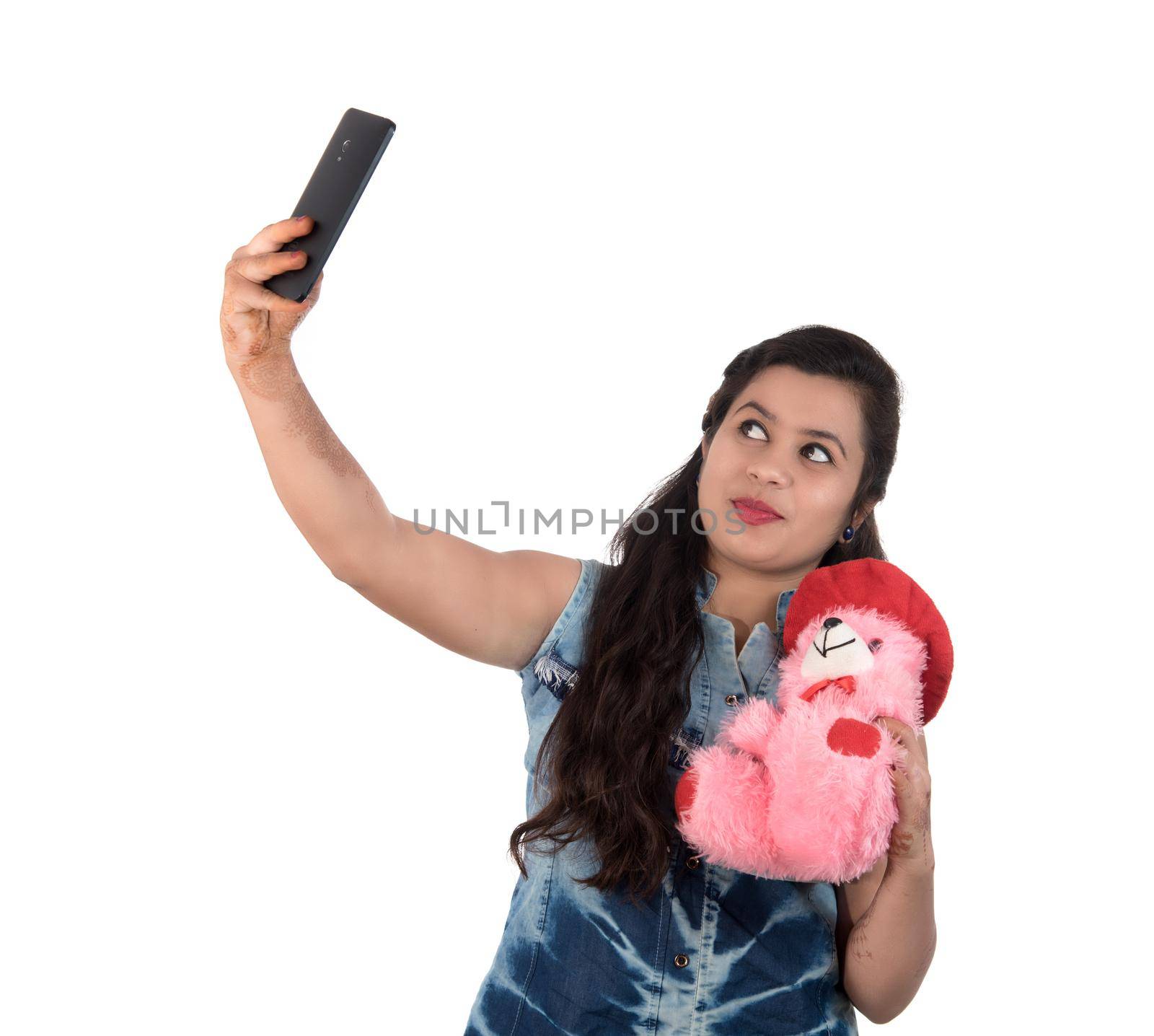 Woman taking picture or selfie with mobile phone and holding teddy bear