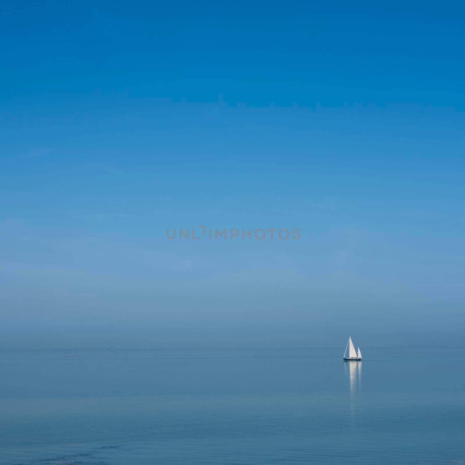 lonely sailing vessel on blue water of vast empty lake under blue sky in dutch province of zeeland in the netherlands