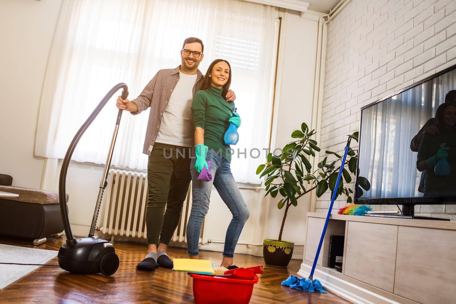 Young happy couple is cleaning their apartment.