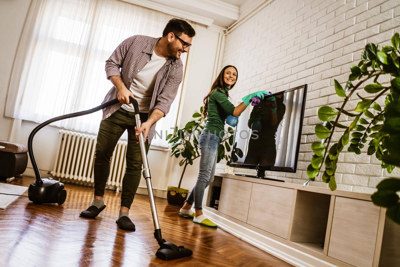 Young happy couple is cleaning their apartment.